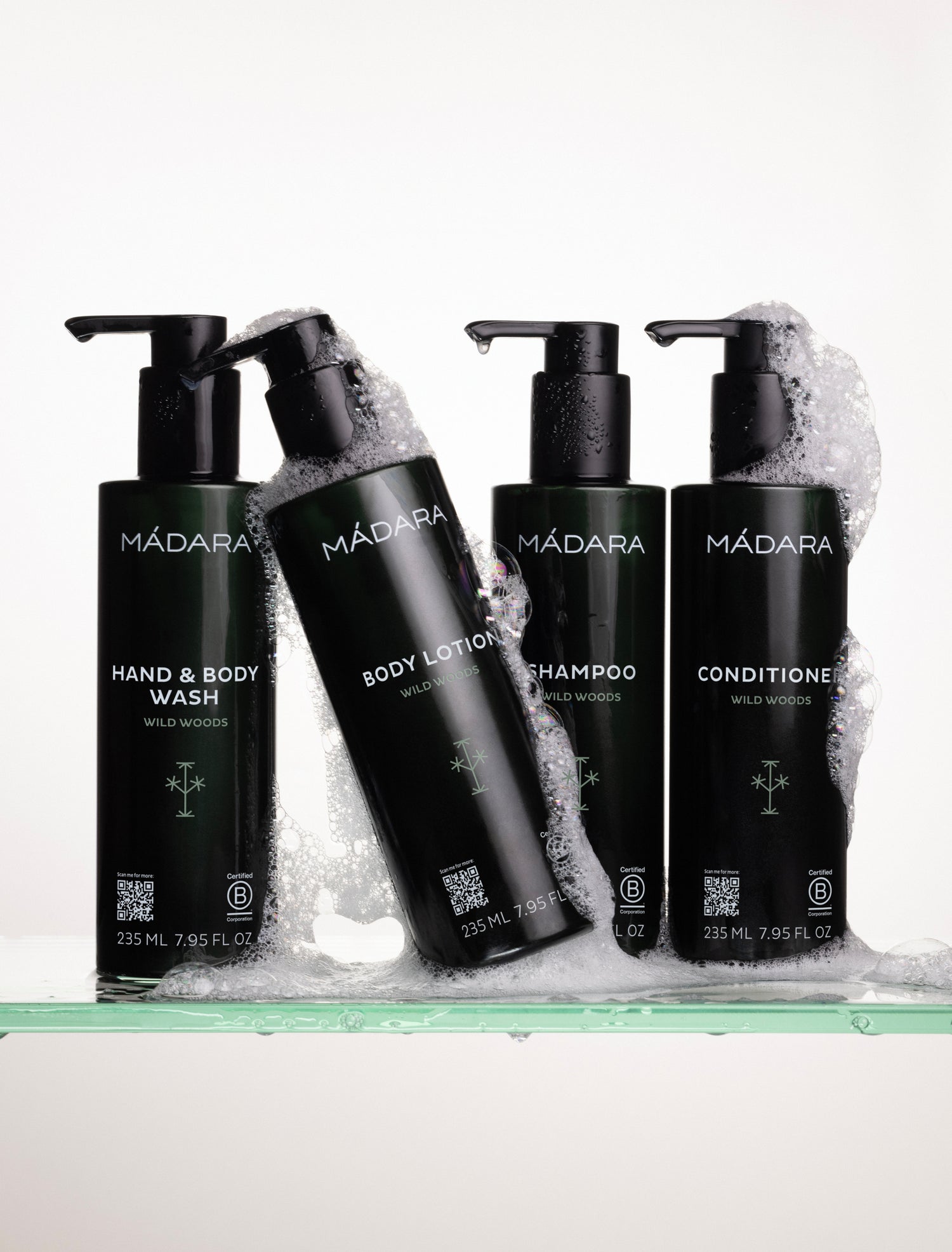 Four black bottles of Mádara skincare products with pump dispensers on a white background.