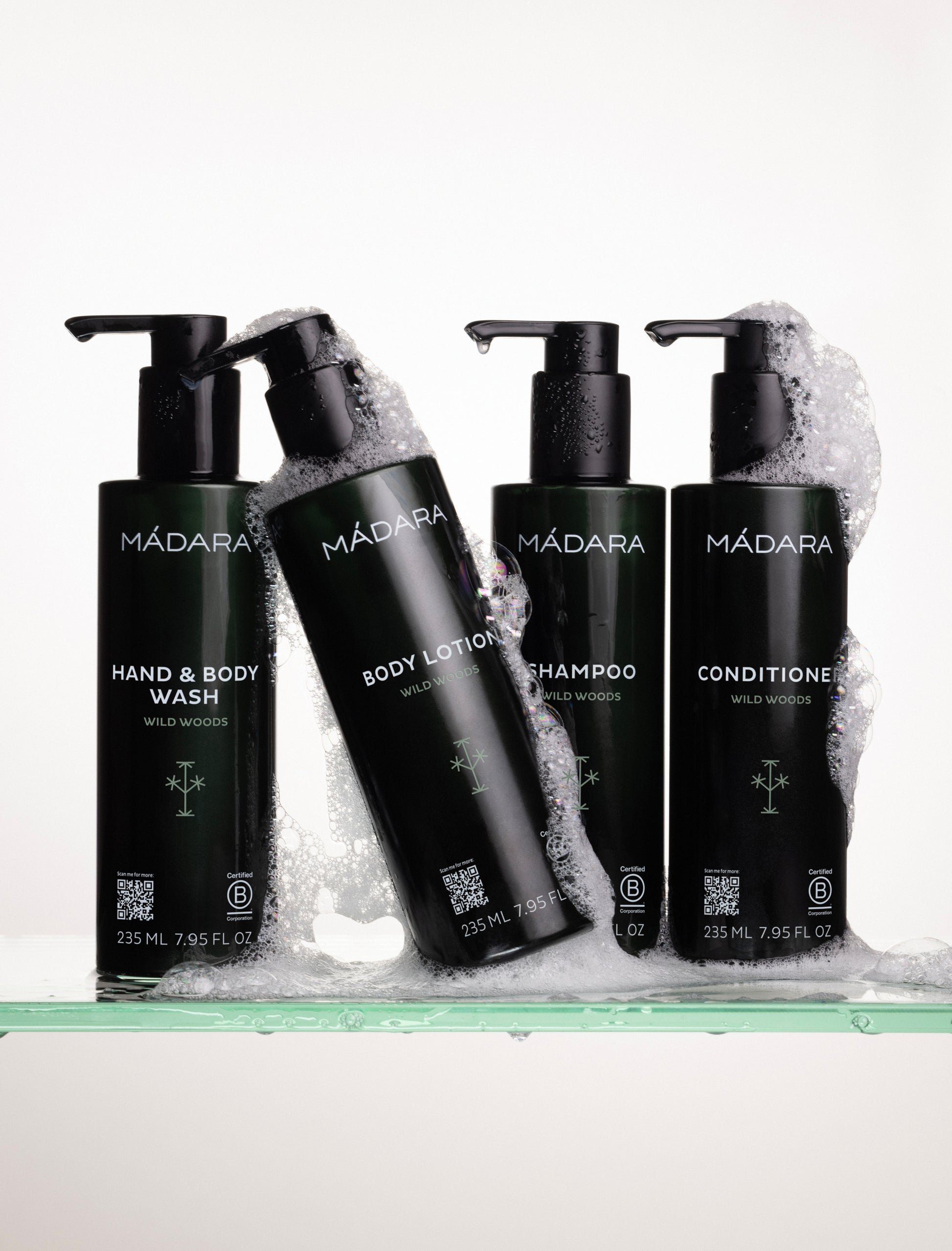Four black bottles of Mádara skincare products with pump dispensers on a white background.