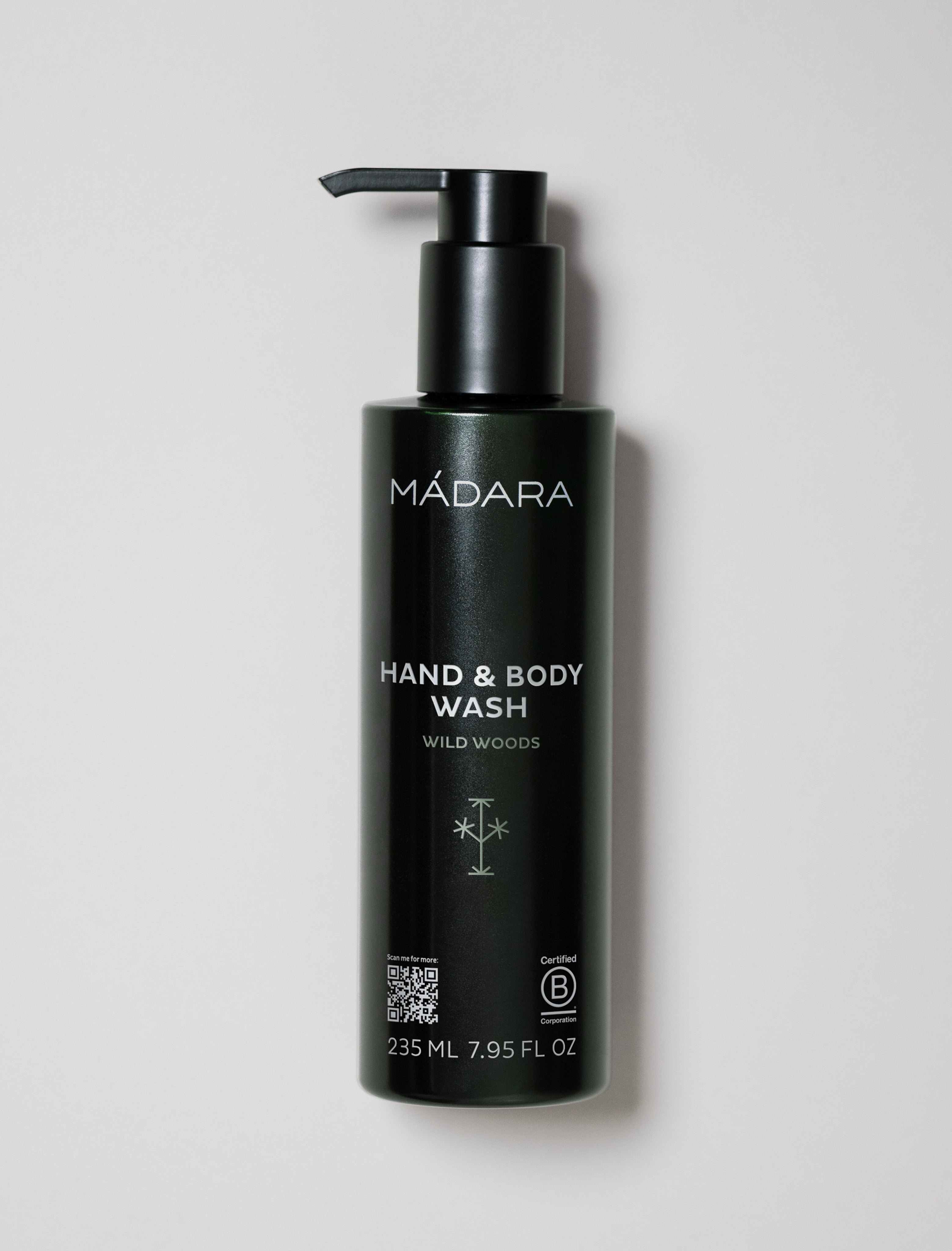 Black bottle of Mádara hand and body wash on a light gray background