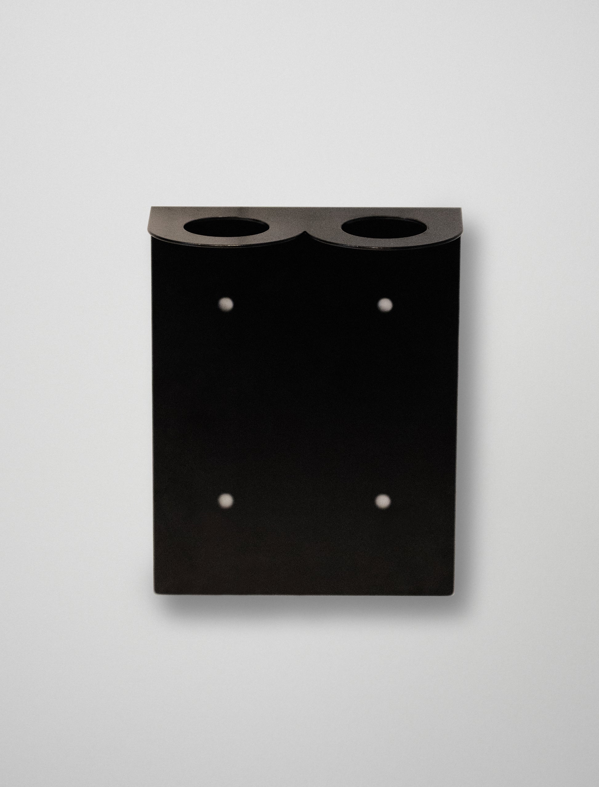 Black soap stend with two circular holes on a light gray background