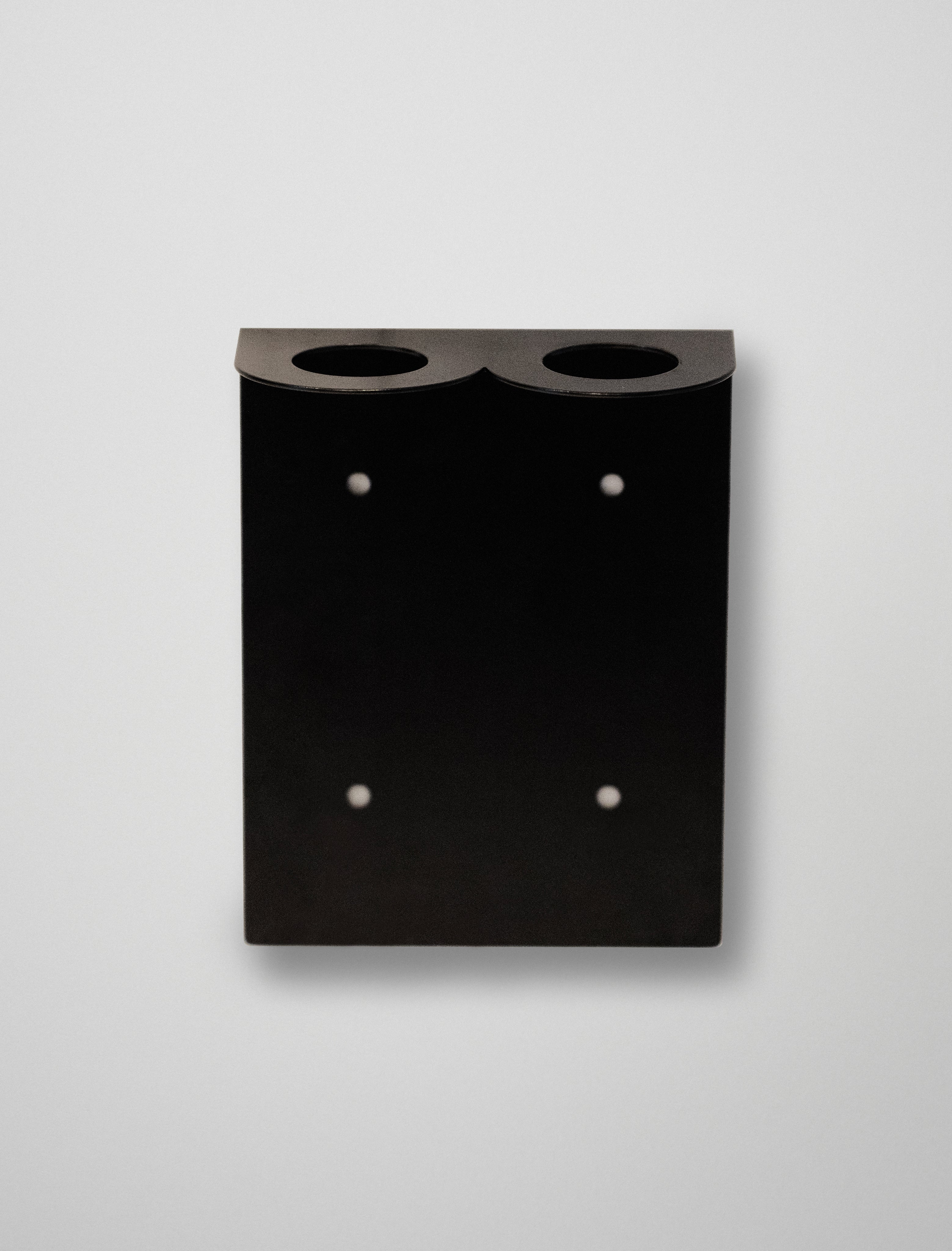 Black soap stend with two circular holes on a light gray background